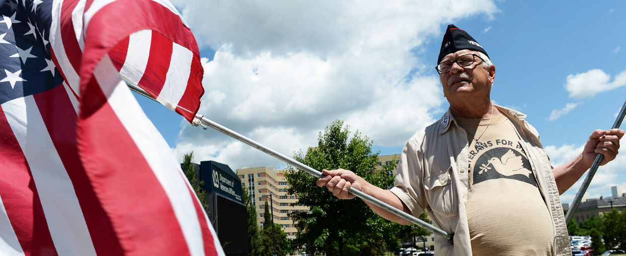 Dan Wilcox, of Albany holds flags in front of the Stratton VA Medical Center 