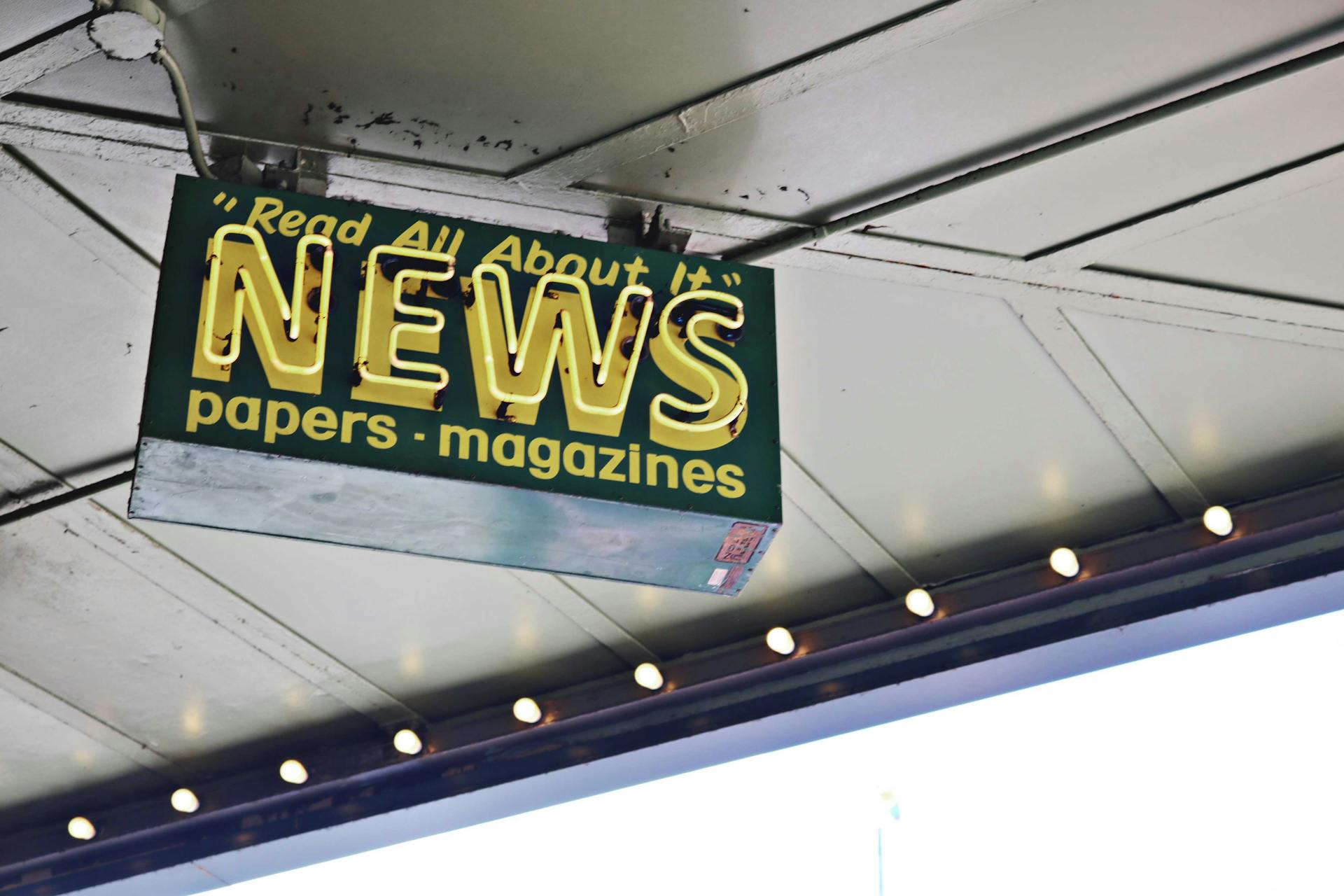 News inscription on neon signboard hanging on street